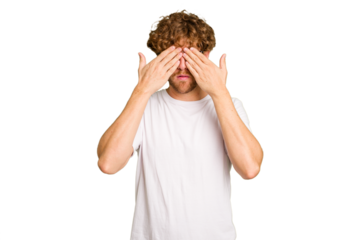 Young caucasian man isolated on green chroma background afraid covering eyes with hands.