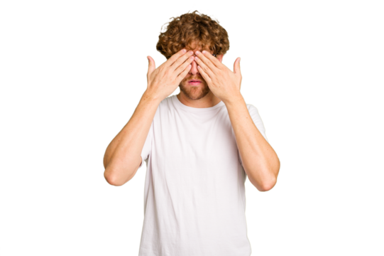 Young caucasian man isolated on green chroma background afraid covering eyes with hands.