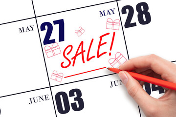 Hand writing text SALE and drawing gift boxes on calendar date May 27. Shopping Reminder