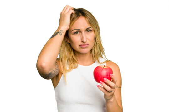 Young caucasian woman holding an apple isolated on green chroma background being shocked, she has remembered important meeting.