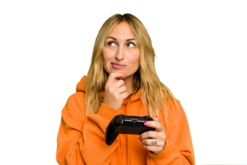 Young caucasian gamer woman holding a game controller isolated on green chroma background looking sideways with doubtful and skeptical expression.