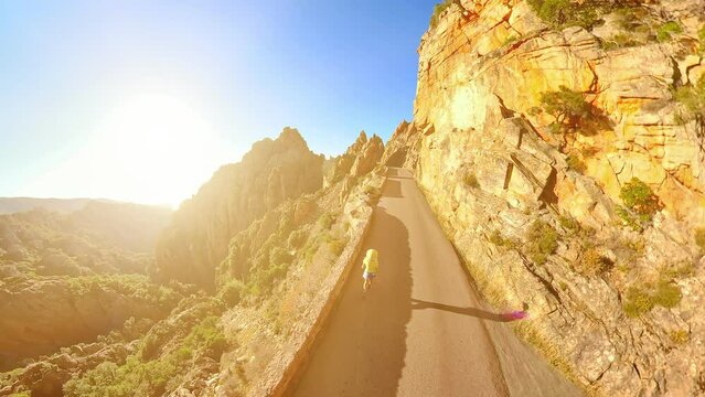 Aerial view of tourist girl walking on D81 route of Calanques of Piana badlands at sunset. Drone view Corsican badlands called Les Calanques in Mediterranean sea by the Porto Ota and UNESCO heritage.