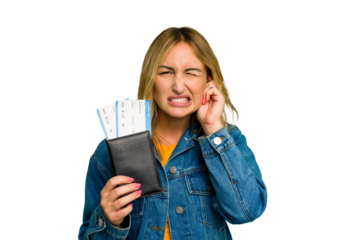 Young caucasian woman holding a passport isolated on green chroma background covering ears with hands.