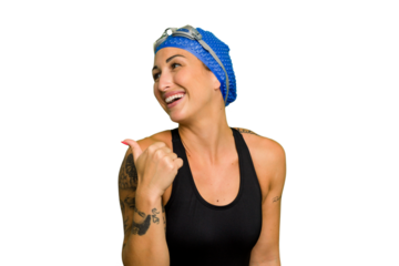 Young caucasian swimmer woman isolated on green chroma background points with thumb finger away, laughing and carefree.