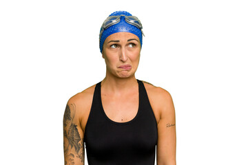 Young caucasian swimmer woman isolated on green chroma background confused, feels doubtful and unsure.