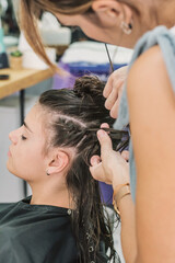 A Person Having A Weave Hair Extension Braided In An Urban Real-Life Salon. Woman At The Hairdresser. Female hairdresser while working.