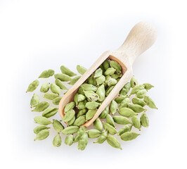 Green cardamom in wooden scoop isolated on white background