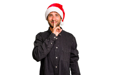 Young caucasian man celebrating Christmas wearing a santa hat isolated keeping a secret or asking for silence.