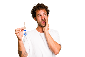 Young caucasian man holding home keys isolated is saying a secret hot braking news and looking aside