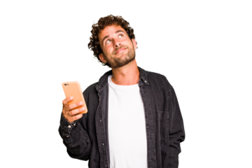 Young caucasian man using mobile phone isolated dreaming of achieving goals and purposes