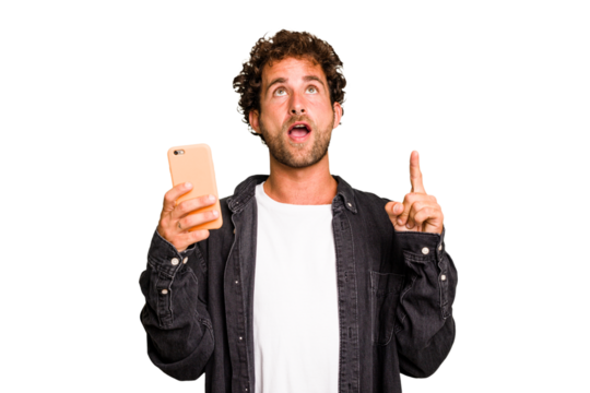 Young caucasian man using mobile phone isolated pointing upside with opened mouth.