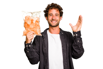 Young caucasian man holding crips isolated receiving a pleasant surprise, excited and raising hands.