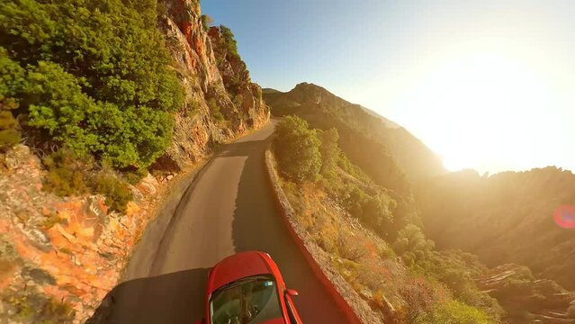 Aerial view of Les Calanques of Piana, a natural park of Corsica on the Mediterranean and UNESCO heritage. Red car on the road D81 route of the Piana Badlands at twilight with heart-shaped stone.