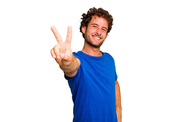 Young caucasian curly hair man isolated Young caucasian man with curly hair isolated joyful and carefree showing a peace symbol with fingers.