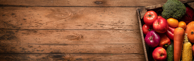 Fototapeta premium wooden background with fresh juicy vegetables and fruits in a copyspace box on an empty wooden table, panoramic photo.