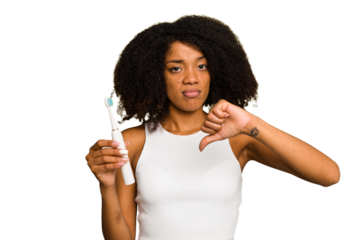 Young african american woman holding an electric toothbrush isolated showing a dislike gesture, thumbs down. Disagreement concept.