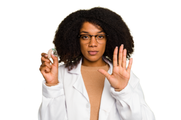 Young otorhinolaryngologist African american woman holding hearing aid isolated standing with outstretched hand showing stop sign, preventing you.