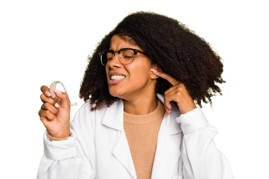 Young otorhinolaryngologist African american woman holding hearing aid isolated covering ears with hands. - Powered by Adobe