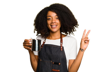 Young African American woman barista isolated joyful and carefree showing a peace symbol with...