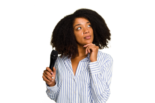 Young African American singer woman holding a microphone isolated looking sideways with doubtful and skeptical expression.