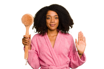 Young African American woman holding a shower brush isolated smiling cheerful showing number five with fingers.
