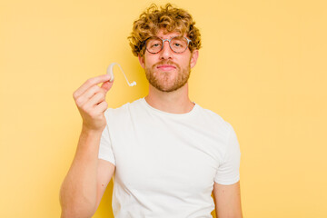Young caucasian man wearing hearing aid isolated on yellow background happy, smiling and cheerful.