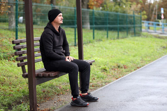 man sitting on bench on bus stop