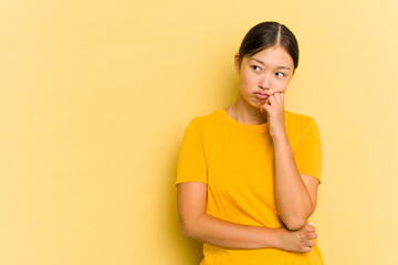 Young Asian woman isolated on yellow background who feels sad and pensive, looking at copy space.