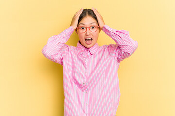 Young Asian woman isolated on yellow background screaming, very excited, passionate, satisfied with something.