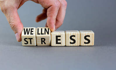 Stress or wellness symbol. Concept words Stress or Wellness on wooden cubes. Businessman hand. Beautiful grey table grey background. Business stress or wellness concept. Copy space.