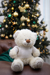 Isolate. White teddy bear on the background of the Christmas tree. Close-up. Copyspace