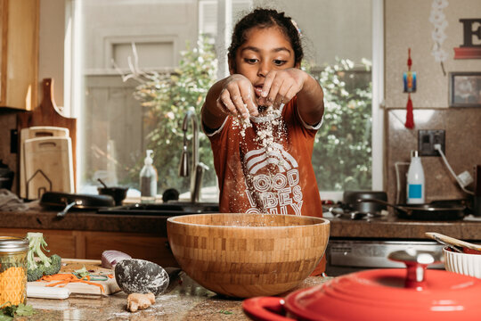 Little girl playing with flour while baking 