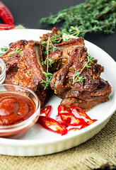 Baked ribs. Roasted pork ribs with spices and herbs on a dark background. Food background. Side view. Close-up. Copy space.