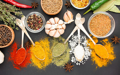 A variety of spices and herbs on a dark table. Cooking background. View from above. Ingredients for cooking. Table background menu.