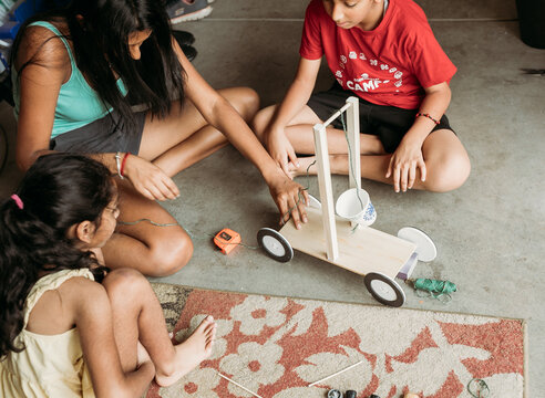 Siblings looking while teen works on a school experiment 