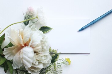 A delicate festive bouquet, a notebook and a pen. Pastel shades. Background for for a greeting card.