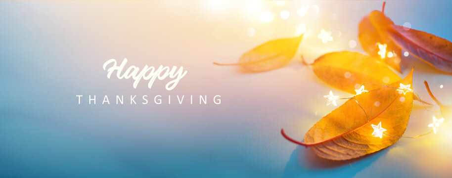 Art happy thanksgiving banner design. autumn yellow leaves and festive lights on a blue background