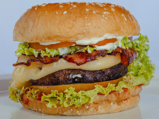 Angus bacon cheeseburger with mayonnaise, ketchup, tomato and lettuce on sesame seed bun