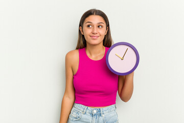 Young Indian woman holding a clock isolated on white background dreaming of achieving goals and purposes