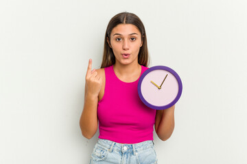 Young Indian woman holding a clock isolated on white background having some great idea, concept of creativity.