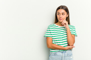 Young Indian woman isolated on white background looking sideways with doubtful and skeptical expression.