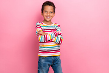 Photo of cute charming schoolboy with curly hairstyle dressed striped long sleeve arms crossed stand isolated on pink color background