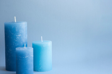Set of blue wax candles for interior design on a blue background. Minimalistic and beautiful accessories. Idea for cold winter gift and decorating home, cafe, shop. Relax and meditation atmosphere.