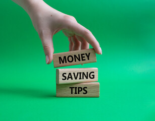 Money saving tips symbol. Concept words Money saving tips on wooden blocks. Beautiful green background. Businessman hand. Business and Money saving tips concept. Copy space.