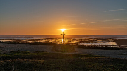 coucher de soleil sur l'île d'Oléron près des falaises et phare de Chassiron au bord de l'océan avec la croix érigée en hommage aux morts en mer