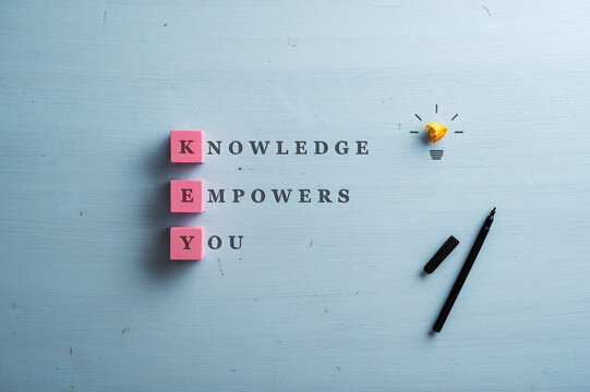 Knowledge empowers you sign written on blue wooden background with the first letter of each word on pink blocks