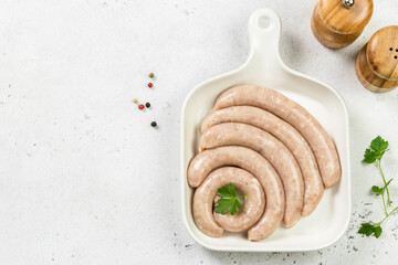 Raw pork sausages on white plate. Top view, copy space.