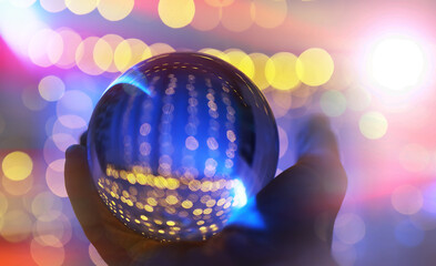 Crystal Ball on the floor with bokeh, lights behind. Glass ball with colorful bokeh light, celebration concept.