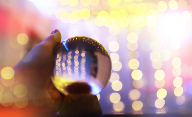 Crystal Ball on the floor with bokeh, lights behind. Glass ball with colorful bokeh light, celebration concept.