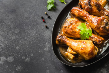 Drumsticks air fryer chicken legs in cast iron skillet on dark background. Top view, copy space.